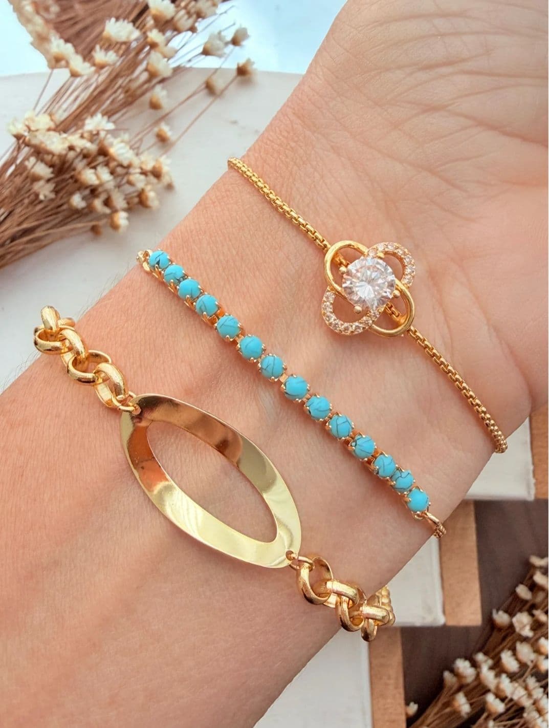 Pulseiras douradas com detalhes em pedras e turquesa, representando a elegância das semijoias Luz da Luna